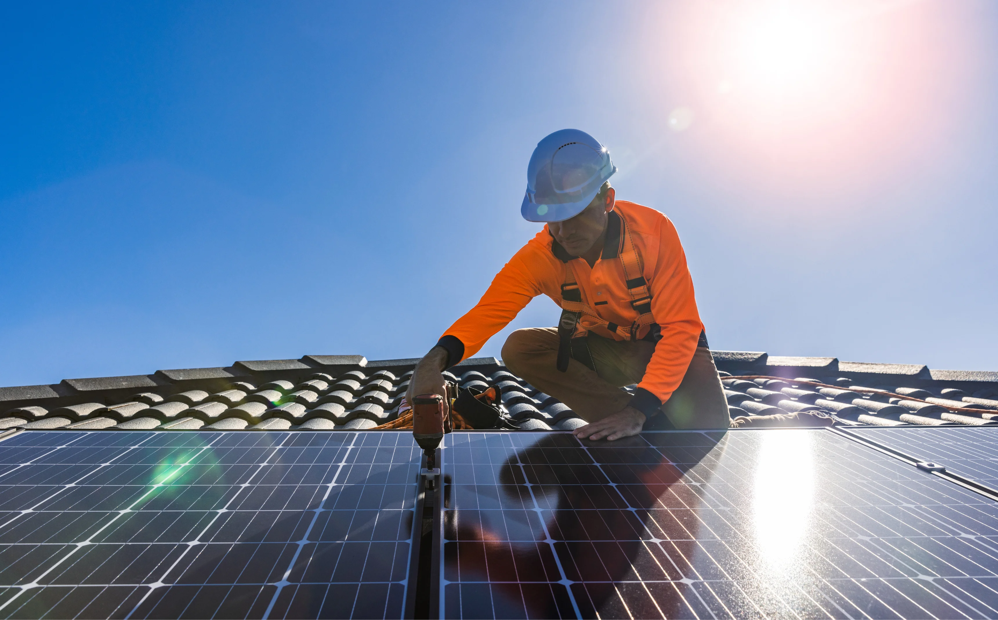 Professional SAA Accredited solar installer safely working on Australian tiled roof with proper safety equipment
